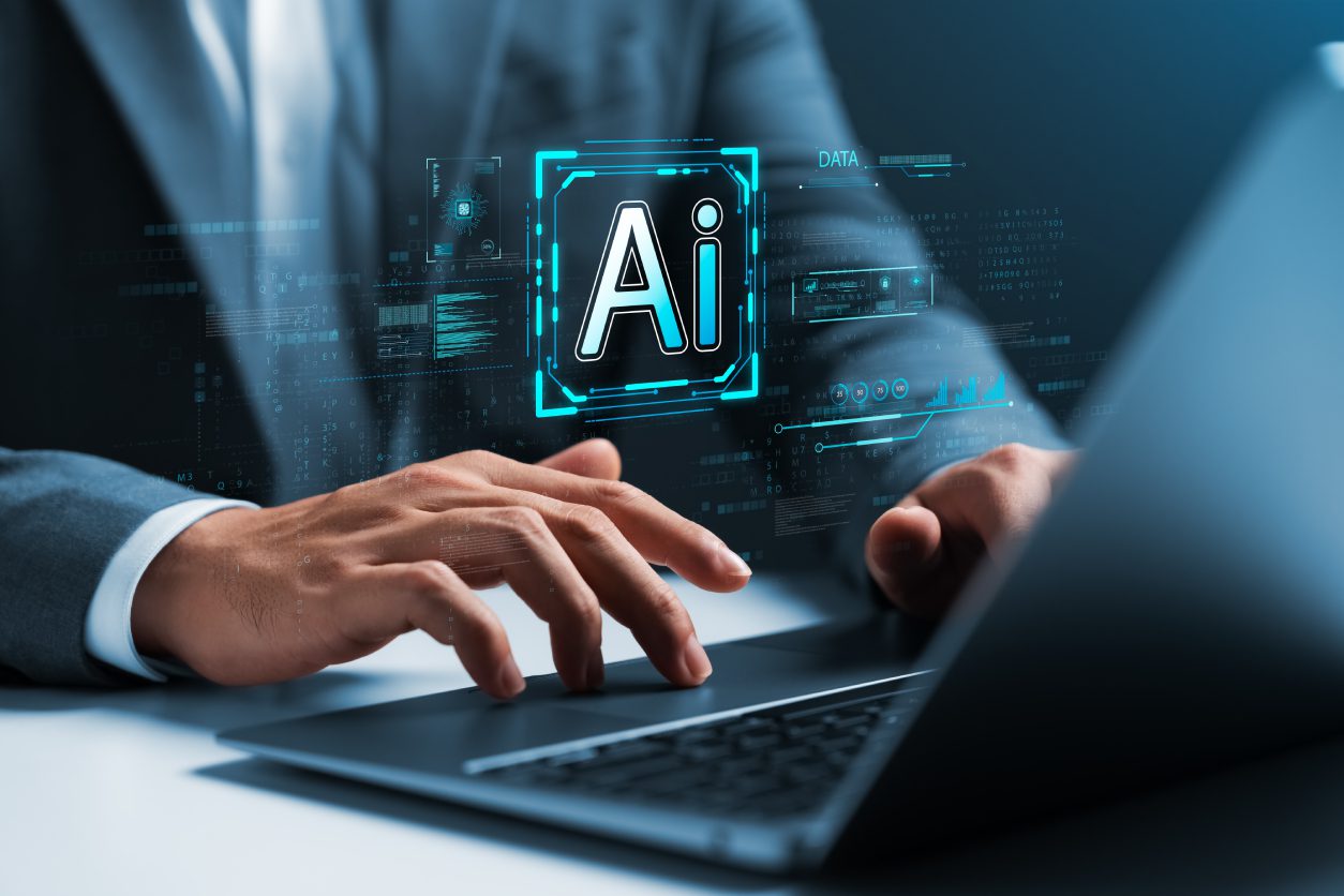 Person typing on laptop with AI hologram.